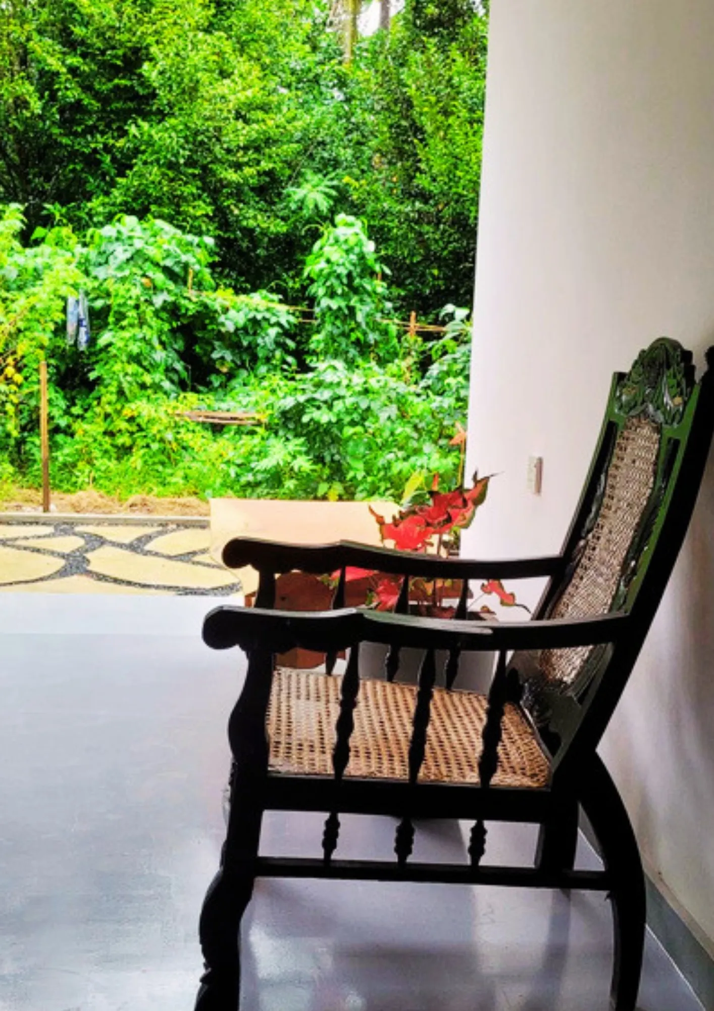 Antique planter's chair on the shaded veranda overlooking the garden at Thepu Villa