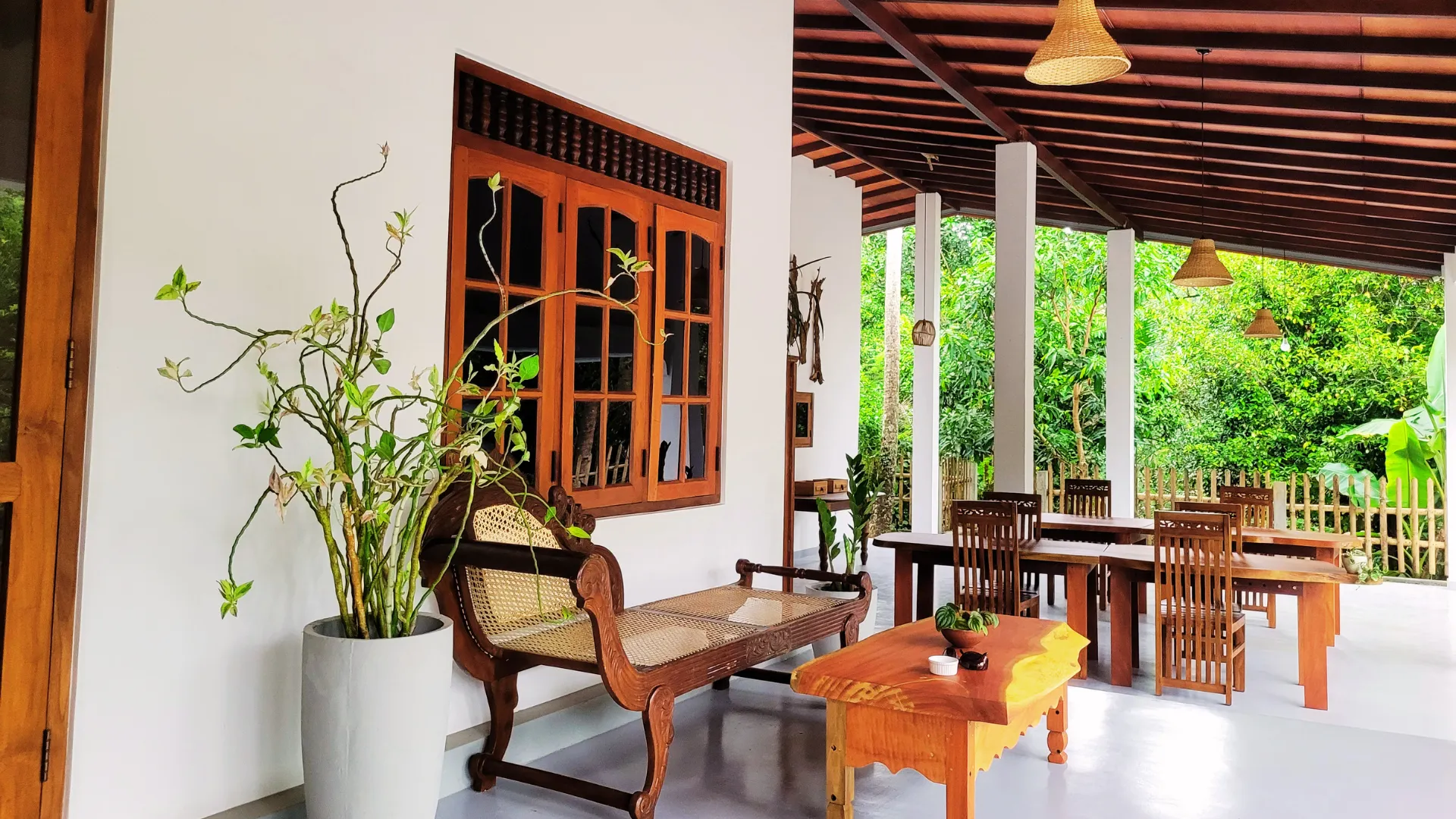 Open-air veranda lounge and dining area with teak furniture at Thepu Villa