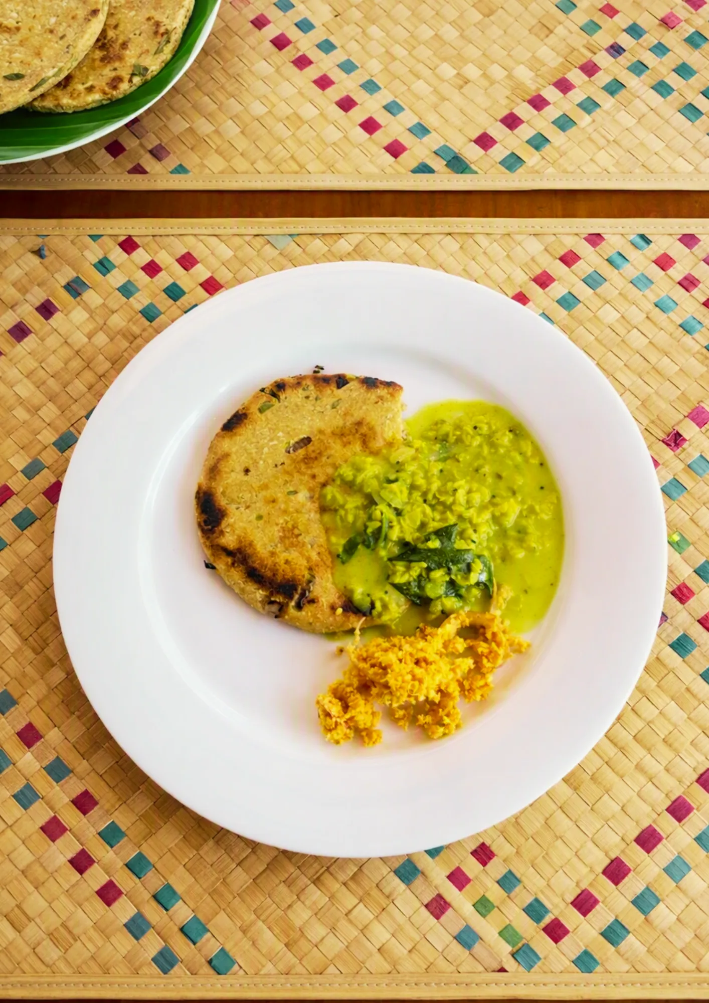Roti with curry and coconut sambol served on a woven placemat